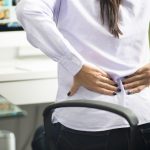 Woman sitting at office having back pain due to bad position or having a not ergonomic chair